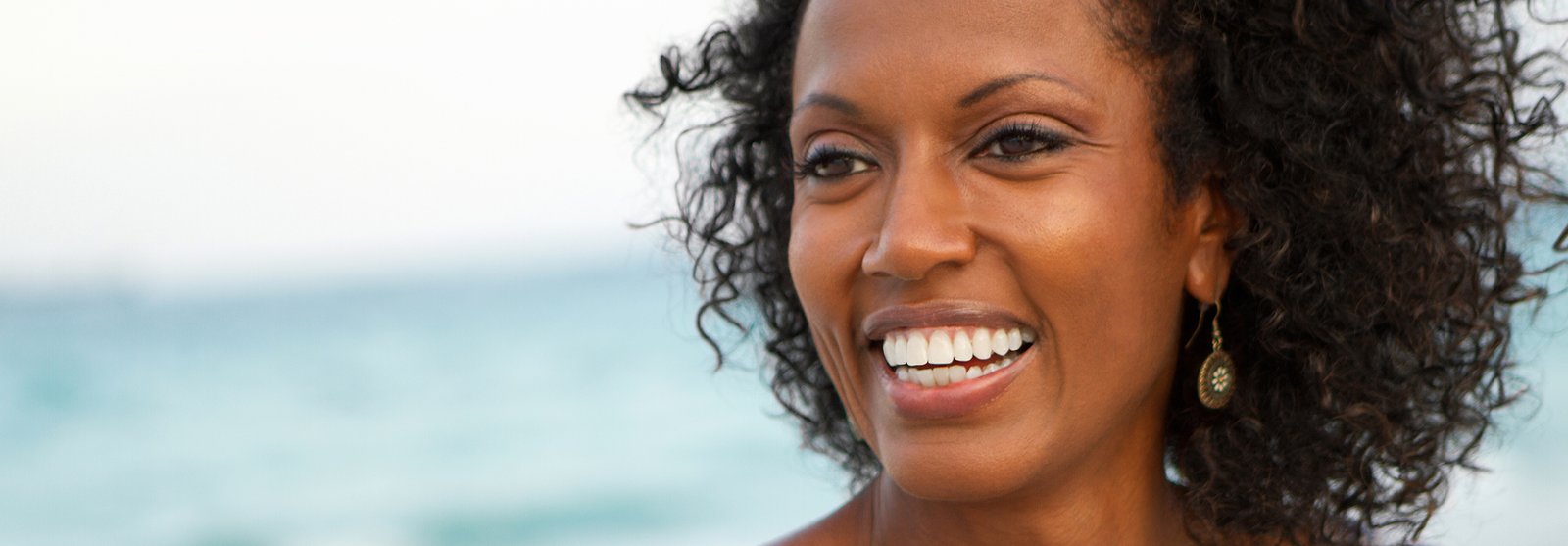 Beautiful woman with curly hair smiling outside