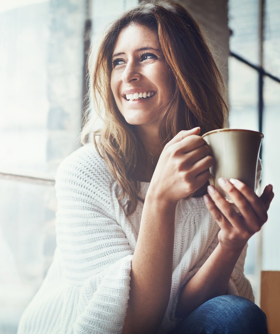 Woman smiling holding a cup of coffee